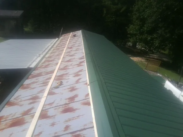 Old rusted panels beside newly installed green metal roofing — Wind Damage Roof Repair by Roofing Brothers in Hardin